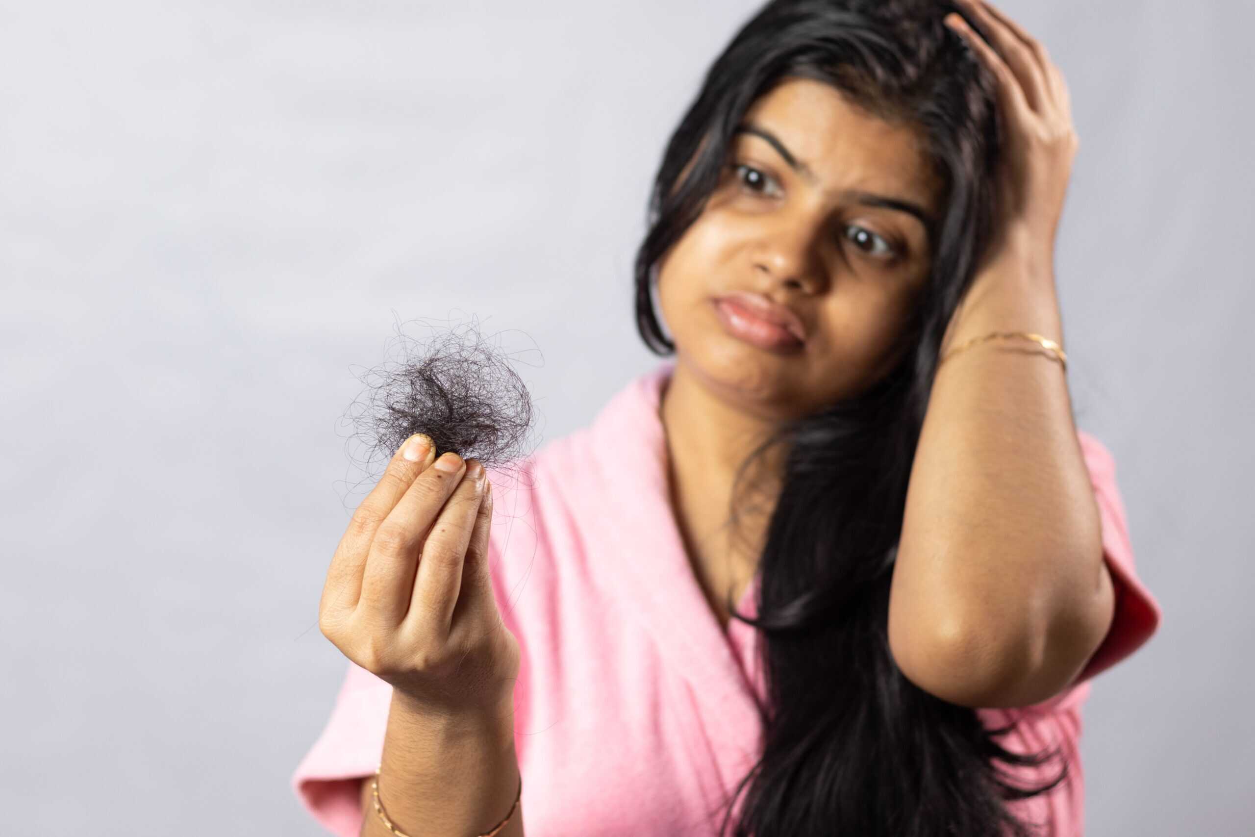 Hair loss concern woman holding hair shed from scalp healthy hair thinning hair treatment.