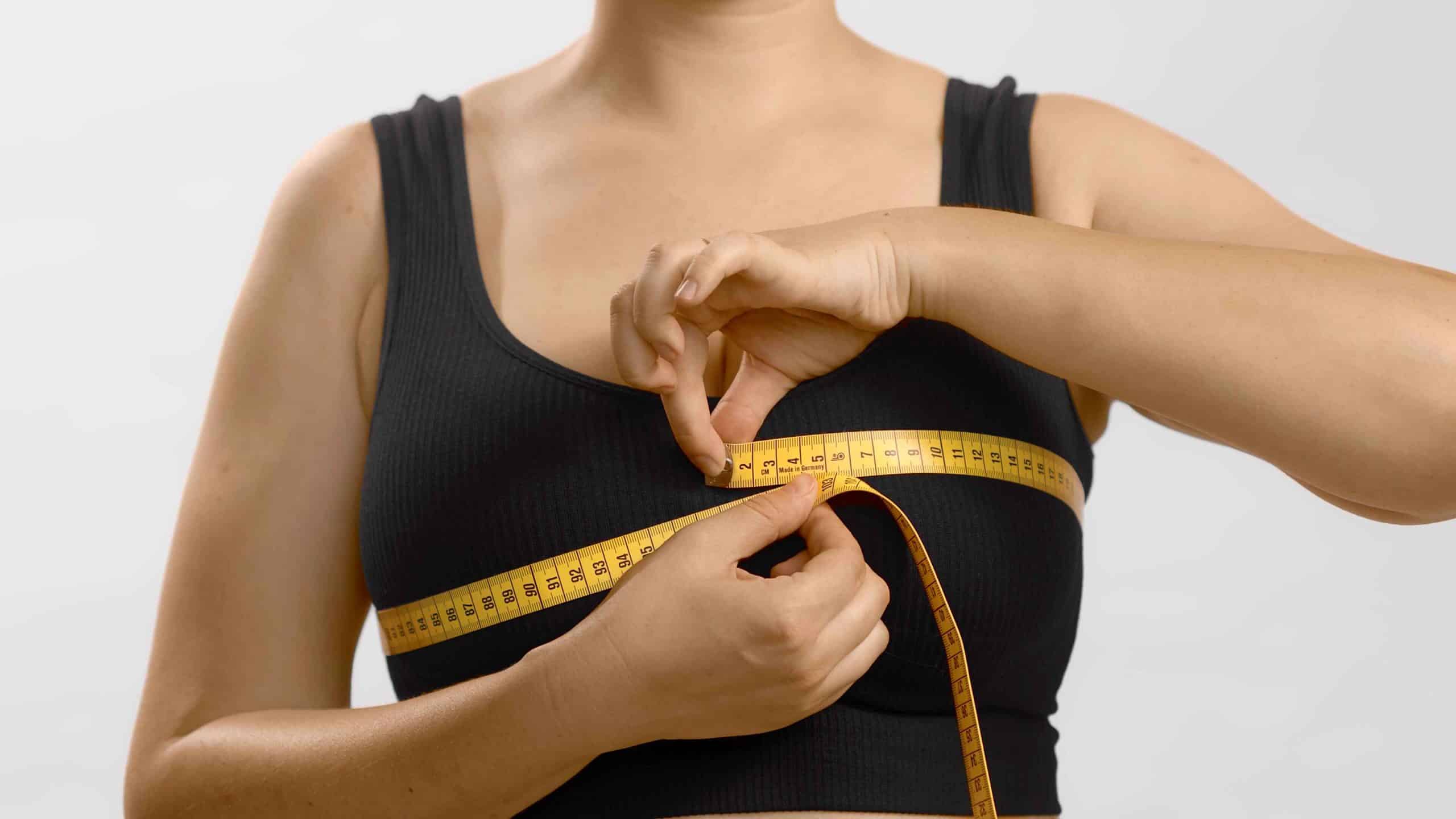 Accurate waist measurement with a yellow tape measure on a woman's black tank top.